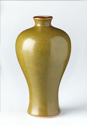  A tall, olive-green glazed vase with a rounded body and narrow neck against a plain, light background. The vase has a lustrous finish with variations in green, imparting a sense of depth and subtle luminosity to its surface. Artist name and title are unknown.