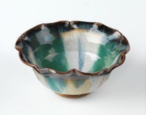  A hand-crafted ceramic bowl with an undulating rim, featuring a spontaneous blend of dark green, cream, and muted turquoise glaze with streaks of dark blue accents. The glaze pattern mimics a watercolor-like effect, creating a unique visual texture.