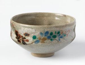  A handcrafted ceramic bowl with three small feet, featuring a textured beige and light grey exterior decorated with subtle red, orange, blue, and green floral motifs and butterfly-like insects. The interior is a uniform grey. Artist and title are unknown.