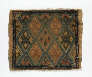 
 Antique textile with a geometric diamond lattice pattern in olive green and alternating diamond motifs in rusty orange and golden-yellow on a faded black background, showing signs of age and wear.