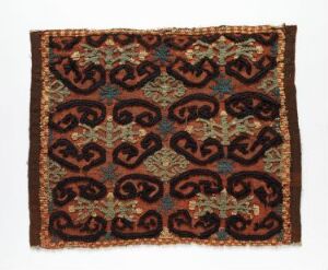  A square textile featuring an intricate pattern with stylized dragon-like motifs in shades of brown, red, orange, accented with teal and black, framed by concentric borders with additional geometric motifs.