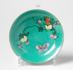  Decorative ceramic plate with a vibrant turquoise glaze, adorned with a botanical and butterfly design in pinks, greens, and oranges, displayed on a clear stand.