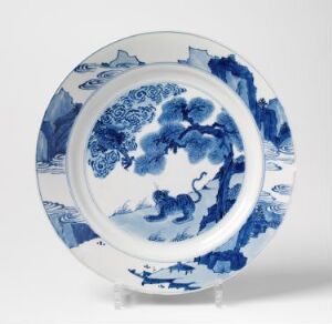  A traditional blue and white porcelain plate with intricate blue designs on a white background, featuring a central decorative motif surrounded by smaller landscape scenes and various patterns along the rim.