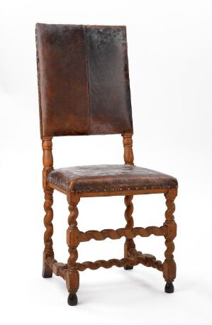  An antique wooden chair with dark brown leather upholstery on the seat and backrest, featuring ornately turned legs, and decorative woodturning details, set against a plain white background.