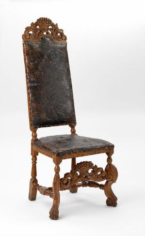  An antique wooden chair with a high, arched backrest featuring elaborate carvings of scrolls and flowers, and a seat upholstered in aged, dark brown or black leather. The chair's ornate legs and supports match the styling of the backrest, all set against a light gray background.