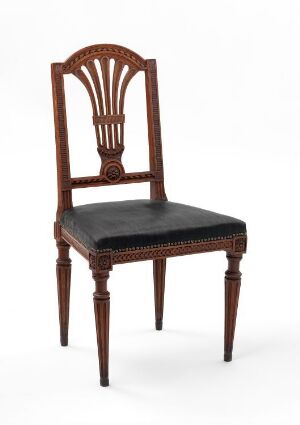  An antique neoclassical style wooden chair with a sunburst motif on the backrest and black upholstered seat, set against a soft grey background.