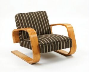  An Alvar Aalto-designed armchair with form-bent birch veneer and striped wool upholstery set against a white background. The chair features distinctive curved armrests and L-shaped legs, exhibiting a harmonious blend of warm wooden tones with vertical stripes in dark brown and sandy tan.