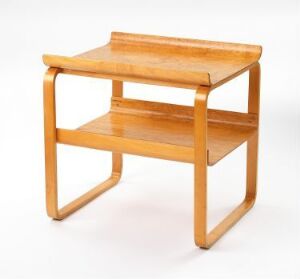  Alvar Aalto's lacquered birch table design, showcasing a warm honey-toned finish with a rectangular top and a lower shelf, supported by arched, bent wooden legs on a plain background.