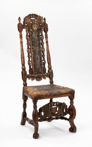  An antique wooden chair with a high, ornate backrest featuring detailed carvings of scrolls and floral motifs, and a central emblem. Warm brown in color, the chair has a worn upholstered seat and elaborate turned legs with decorative braces.