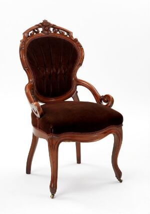  Elegant Victorian-style armchair with a carved wooden frame and dark brown velvet upholstery against a plain background.