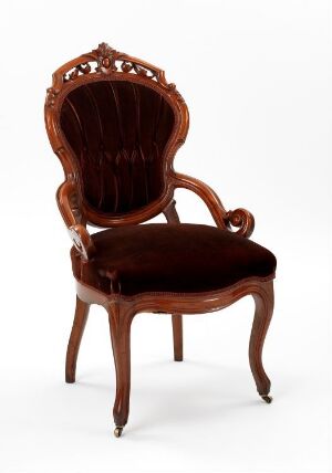  A traditional mahogany armchair with a scalloped top, intricately carved details, softly curved armrests, and a plush, dark-colored seat cushion, exemplifying classic elegance and craftsmanship.