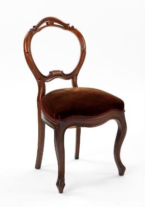  An elegant wooden chair with a heart-shaped backrest and plush maroon velvet seat, exhibiting a warm, polished finish, and standing against a neutral background.