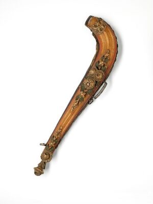  An ornate, golden-brown stringed instrument with a curved neck and a carved scroll, adorned with dark floral patterns, against a light background.