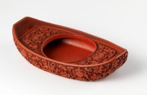 
 A small, decorative terracotta-colored boat-shaped object with an intricate lace-like textured exterior, set against a light background.