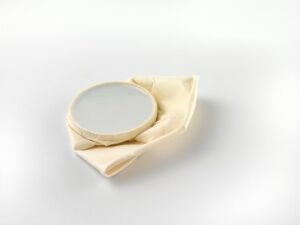  "Street-ware" by Kjell Rylander, a sculpture made of porcelain resembling a crumpled piece of paper with a smooth, circular central area, set against a neutral background.