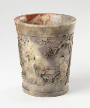  An ancient marbled stone cup with a relief carving depicting classical figures, in colors of creamy beige, earthy vermilion, and cloudy white, suggesting historical significance and artistry.