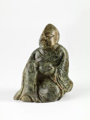  A small, green patina figurine of a seated, robed figure with folded hands and a serene expression, against a plain white background. Artist and title unknown.