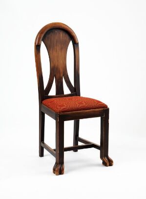  A dark brown, stained pine wood chair with an oval backrest opening designed by Rudolph Thygesen. The seat is upholstered in red textile, contrasted with elaborate clawfoot details on the front legs.