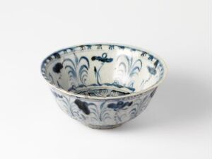  A small, hand-painted porcelain bowl with blue floral and botanical designs on a creamy white background.