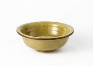  A simple, golden-brown metallic bowl with a smooth, polished surface on a white background. The bowl's design is minimalist with a slightly everted rim and a flat base. Artistname and title are unknown.