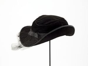  A vintage black velvet women's hat with a bow and a delicate netted veil, displayed against a light gray background.