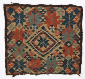  An aged and intricately patterned textile fragment featuring geometric designs in earthy tones, with a central diamond motif surrounded by multiple borders, in colors predominantly of terracotta, rust, olive green, and dark blue, with the textile showing signs of wear and frayed edges. Artist and title unknown.