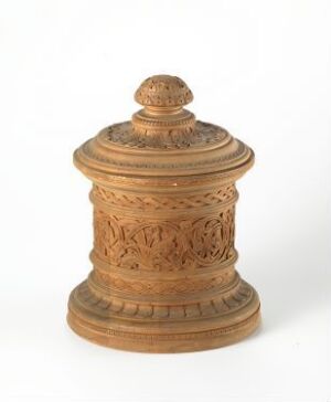  A cylindrical, intricately carved wooden object, possibly a container with a lid, displaying rich folk or classical patterns, on a white background.