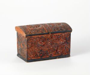  A small antique chest with a hinged lid, elaborately decorated with intertwined floral patterns in reddish-brown, black, and dark gold, showing signs of age and wear.