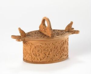  An ornate oval-shaped terracotta pot with detailed embossed floral patterns, featuring two bird figures as handles on the lid, set against a plain white background.