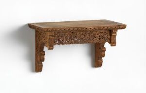  An intricately carved wooden table with geometric and floral patterns, featuring a polished, flat tabletop and thick, sturdy legs against a plain, light background.