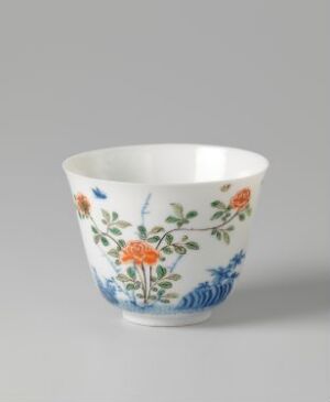  A small, white porcelain teacup or bowl with a flared rim, decorated with an intricate design of orange and blue flowers, and green leaves.