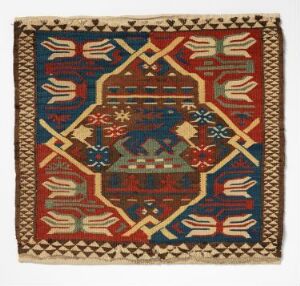  A tapestry with a rich red background and a symmetrical design featuring a central navy blue octagonal medallion, four sets of white outlines of hands pointing inward, and an intricate navy blue border with a Greek key pattern on the edges.