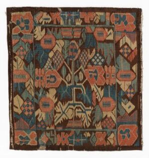  An antique square textile with symmetrical pattern featuring burnt orange, terracotta, beige, and umber hues, accented with teal and blue, displaying traditional geometric motifs suggestive of Middle Eastern or Central Asian artisanship.