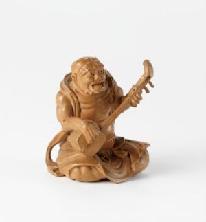  A small, intricately carved wooden figurine of a bearded man seated cross-legged, playing a stringed instrument, and depicted with a highly expressive facial expression, set against a plain white background.