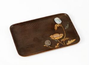  A dark brown, rectangular tray with rounded corners, featuring inlaid or painted designs of a plant with a green leaf and a gold-toned flower with a pearly center, set against an off-white background.