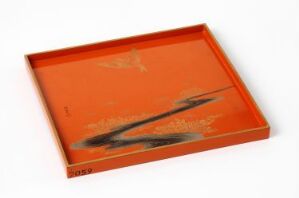  A shallow rectangular tray with a warm orange background and an abstract black and grey smear design in the center, suggesting an artistic or calligraphic expression, set against a white backdrop. The artist's name and title are unknown.