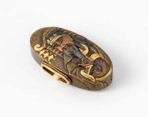  A decorative antique-looking brooch or clasp with a dark brown and golden color scheme, featuring a sculptured surface with a central figure surrounded by stylized motifs that give the impression of bronze or a similarly toned metal with gold highlights.