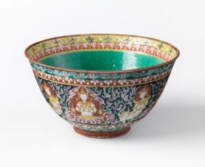  An intricately decorated Bencharong porcelain bowl with an aqua-glazed interior. The exterior is adorned with elaborate patterns and figurative elements in various colors like greens, reds, yellows, and blues on a white background. The bowl's rim features a detailed, colorful band, and it is placed on a plain surface showcasing its artistic detail.