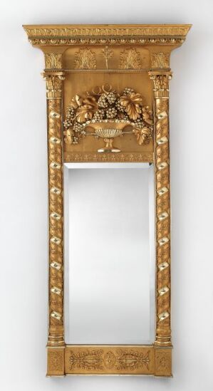  An ornate vertical gold-framed mirror with a highly decorative pediment featuring floral and scroll motifs at the top, and acanthus leaf designs along the sides.