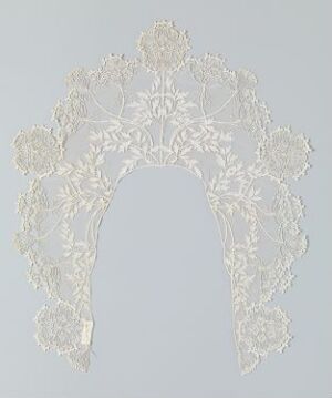  An intricate, white paper cut-out with a lace-like design, featuring symmetrical floral and foliage motifs, set against a light grey background.