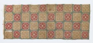  An antique rectangular textile with a grid pattern, featuring intricate red and beige circular motifs within each square framed by a lattice-like design in shades of green and beige, showing signs of age on its fringed edges.