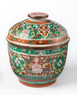  A vibrantly decorated porcelain vessel with a domed lid titled "Tho song taeng" by an unknown artist, featuring a rich sienna base with elaborate green, white, and red enamel motifs including floral patterns and a central figure, showcasing traditional dreiet porselen techniques.