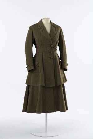  A vintage olive green woman's suit dress on a mannequin, featuring a double-breasted jacket with a notched lapel and a pleated, knee-length skirt, set against a neutral background.