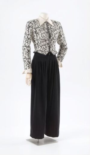  "Trompe-l'oeil romantique nr. 1" by Per Spook, featuring a mannequin dressed in a white blouse with a dense, black lace-like pattern and contrasting high-waisted, wide-legged black silk pants, exemplifying elegant design and fine silk craftsmanship.