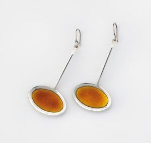  A pair of contemporary silver-framed earrings with amber-colored glassy oblong elements on a white background.