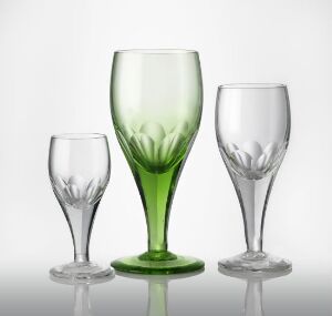  A collection of three blown glass drinking vessels with faceted cut decoration by Ragnvald Hansen, ranging in size and featuring a clear and green color scheme, set against a white background.