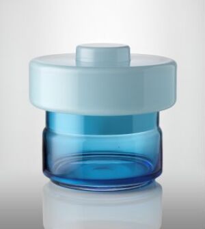  A container from the "Tokyo Box Collection" by Cathrine Maske, exhibiting expertly blown glass technique. The base is a deep translucent blue, above which is a light blue band, transitioning to a frosted teal, topped with a pastel sky blue lid featuring a small knob. The piece radiates a calm and elegant aesthetic.