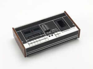 
 The Tandberg TCD 300, designed by Terje Ekstrøm, is a vintage cassette tape deck featuring brushed aluminum, black and white controls, VU meters, and side panels that appear to be palisander wood, embodying a classic industrial design aesthetic.