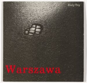  Album cover design by Andrej Nebb titled "Holy Toy - Warzawa" featuring a dark grey, textured background with the title "Holy Toy" in small white letters at the top right corner and a stylized white grenade icon near the top. The title "Warszawa" is written in large, bold red letters at the bottom. The cover reflects a minimalistic style with striking color contrast.