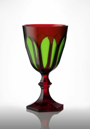  An acrylic goblet designed by Mario Luca Giusti, featuring a deep red color with emerald green flame-like designs, executed with the techniques of casting and dying, creating a visually striking decorative object.